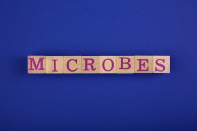 Word Microbes made with wooden cubes on blue background, top view