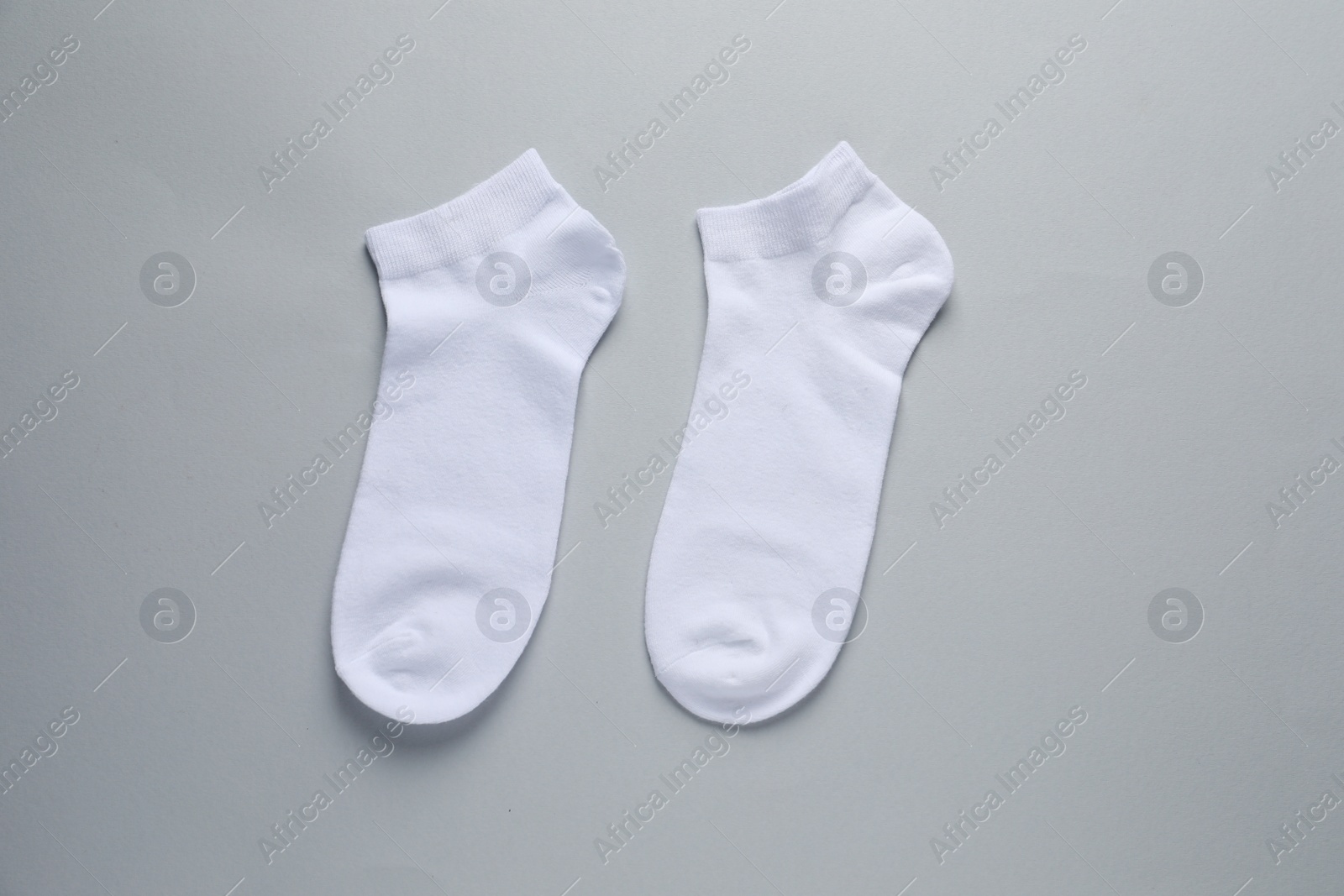 Photo of Pair of white socks on light grey background, flat lay