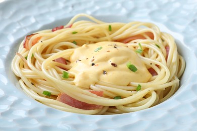 Photo of Delicious spaghetti with meat, cheese sauce and green onion in plate, closeup