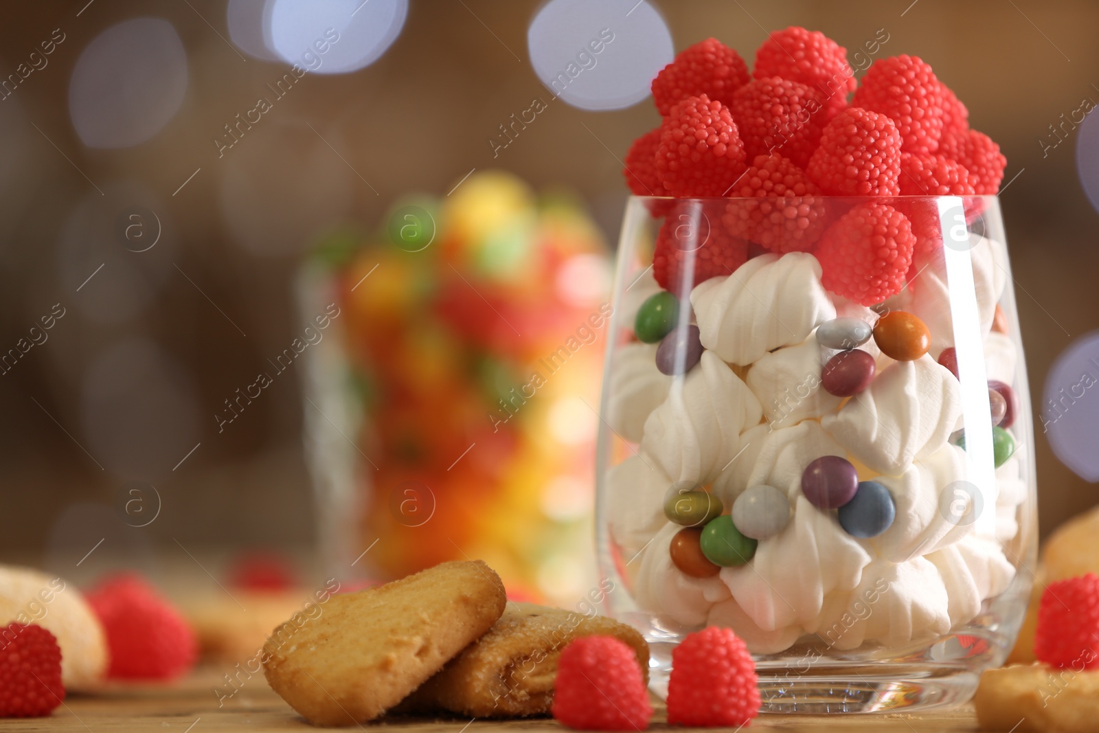 Photo of Delicious candies and cookies on wooden table against blurred background, closeup. Space for text