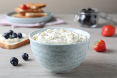 Photo of Tasty cream cheese and fresh berries on white wooden table