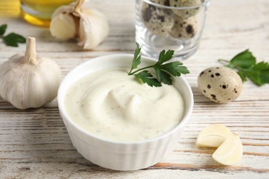 Photo of Composition with bowl of garlic sauce on wooden table