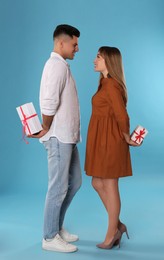 Photo of Lovely couple exchanging gifts on light blue background. Valentine's day celebration