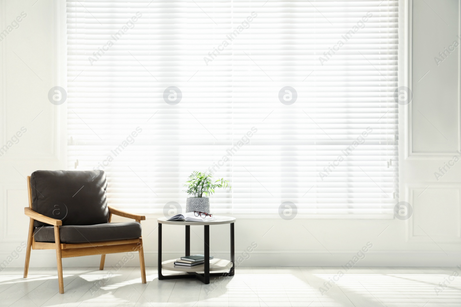 Photo of Comfortable armchair, coffee table and plant near big window in spacious room. Interior design