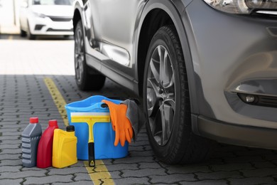 Car cleaning products and bucket near automobile outdoors on sunny day