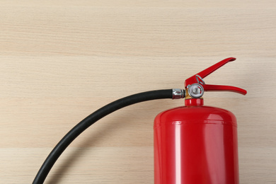Fire extinguisher on wooden background, top view