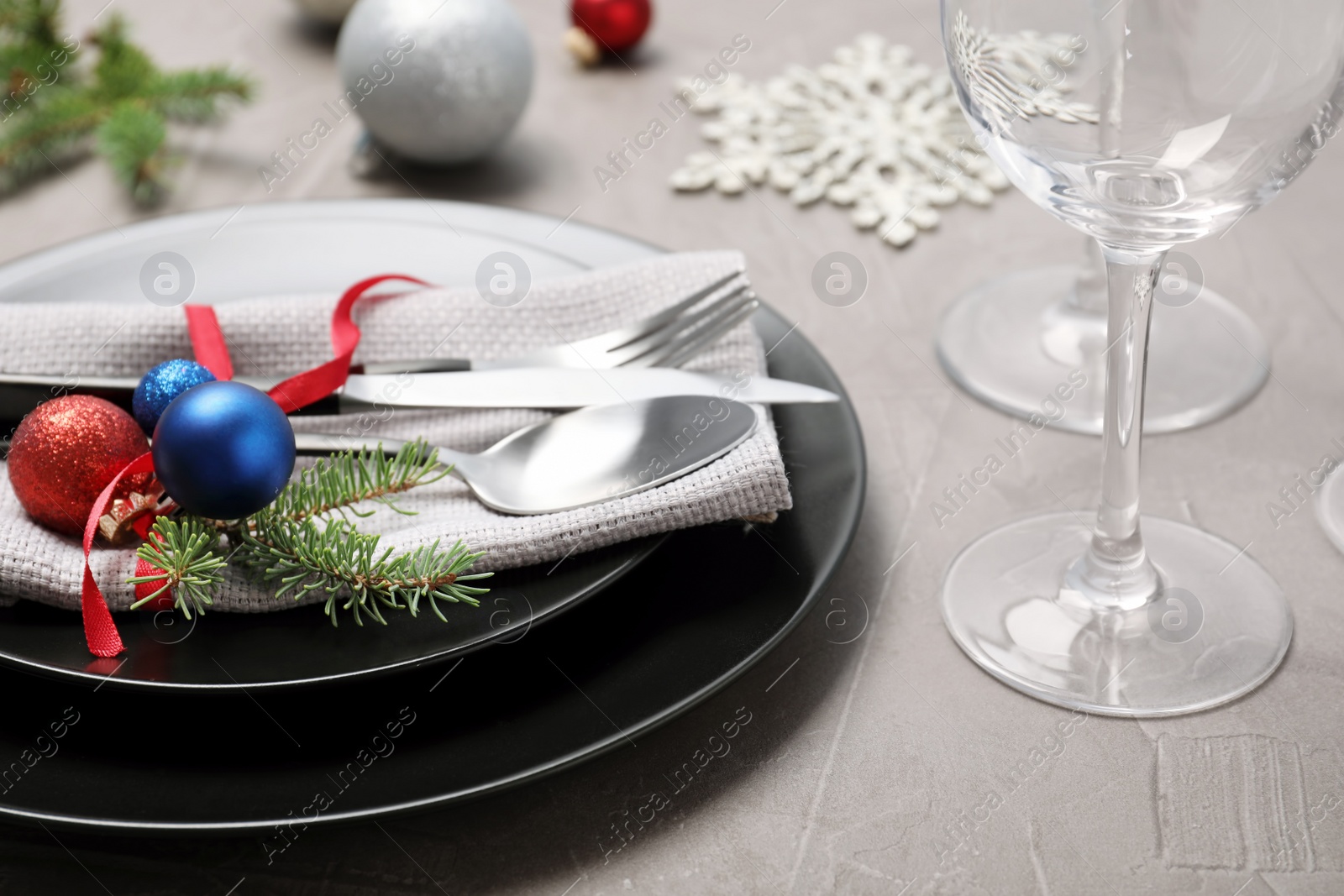 Photo of Christmas table setting with plates, cutlery, napkin and festive decor on grey background, closeup