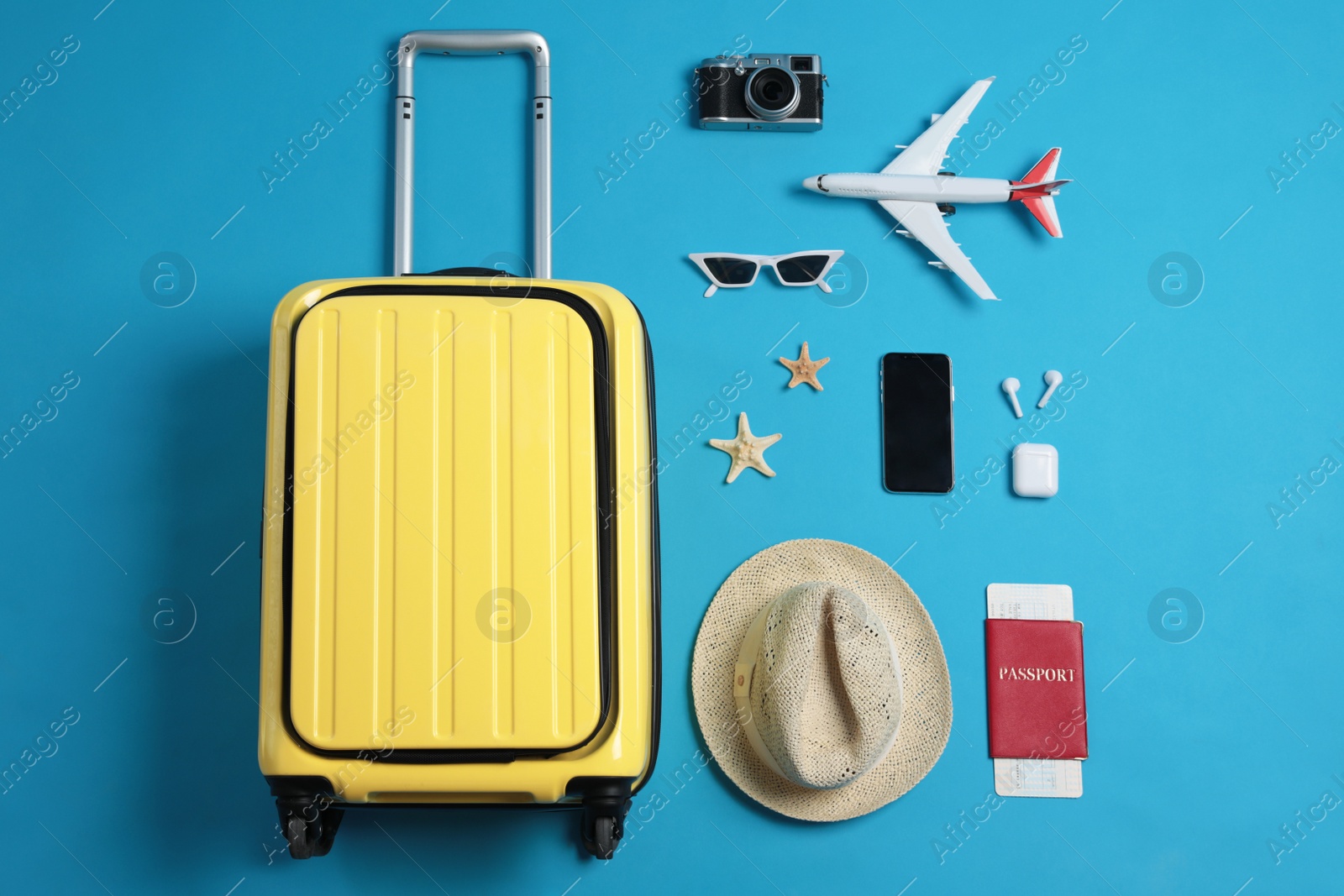 Photo of Flat lay composition with suitcase and travel accessories on light blue background. Summer vacation