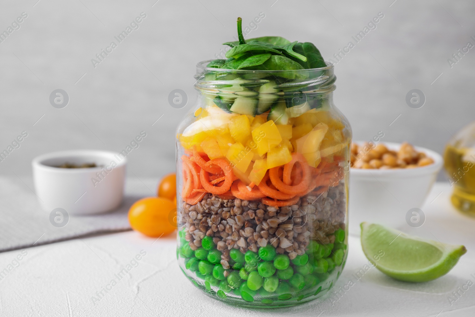 Photo of Healthy salad in glass jar on light table