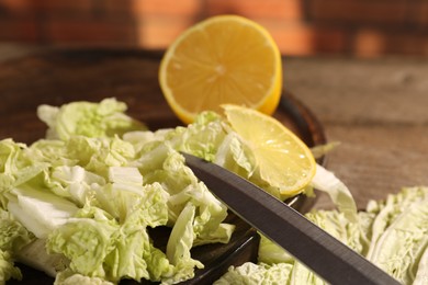 Photo of Fresh Chinese cabbage, lemon and knife on table, closeup