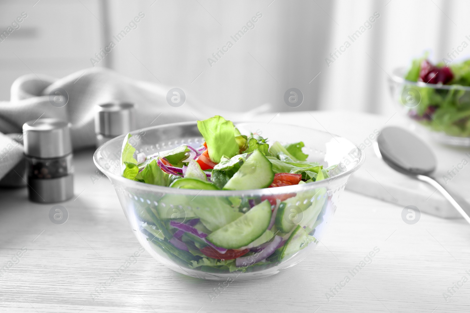 Photo of Bowl of tasty salad with cucumber and lettuce on table