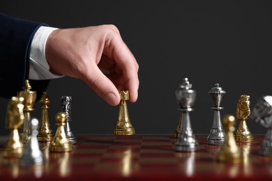 Photo of Man with rook game piece playing chess at board against dark background, closeup