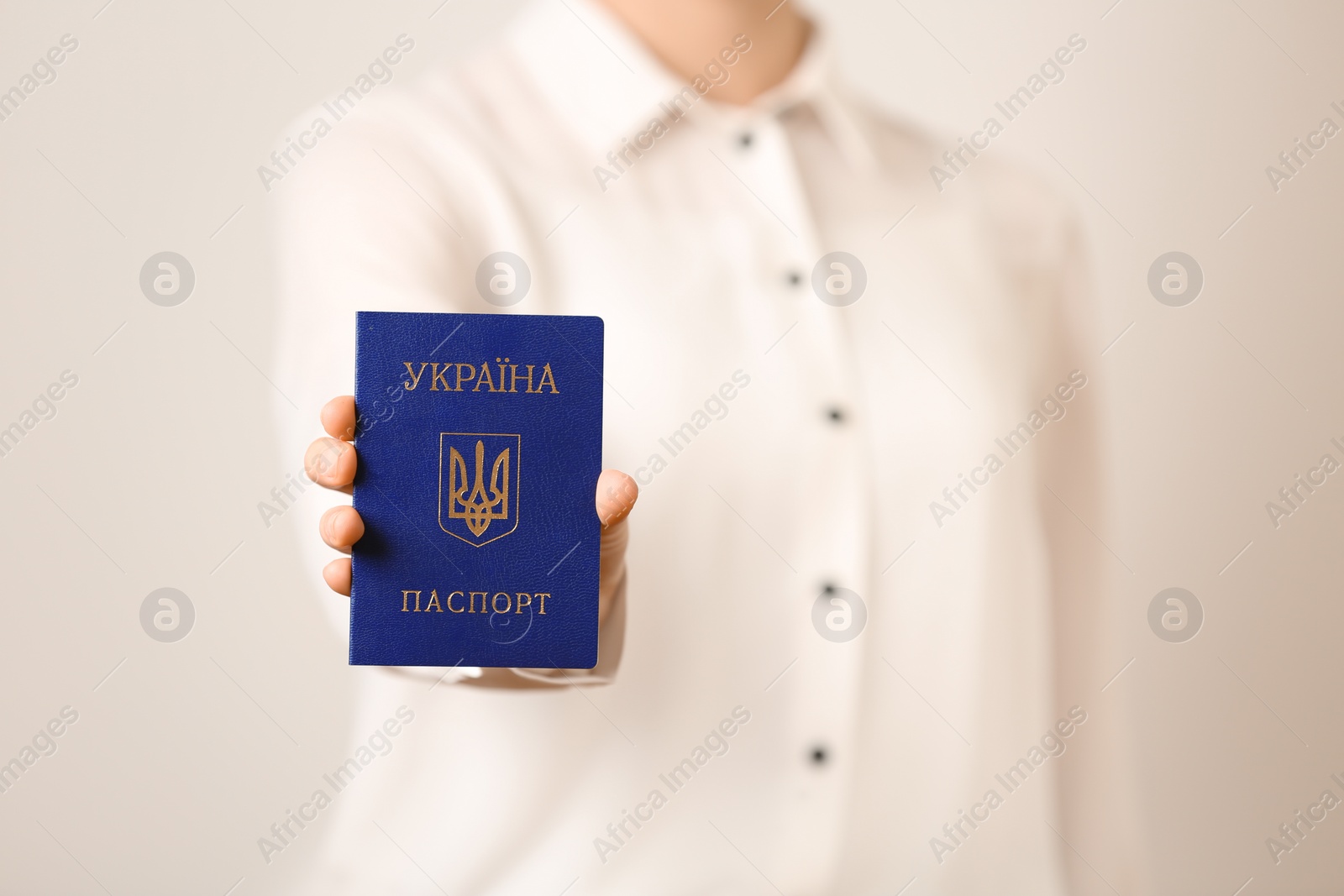 Photo of Woman holding Ukrainian internal passport on light background, closeup