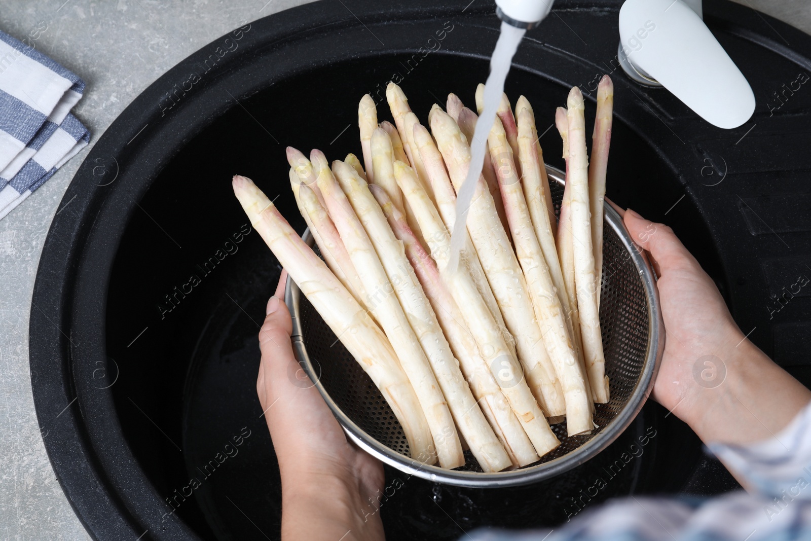 Photo of Woman washing fresh white asparagus over sink, closeup