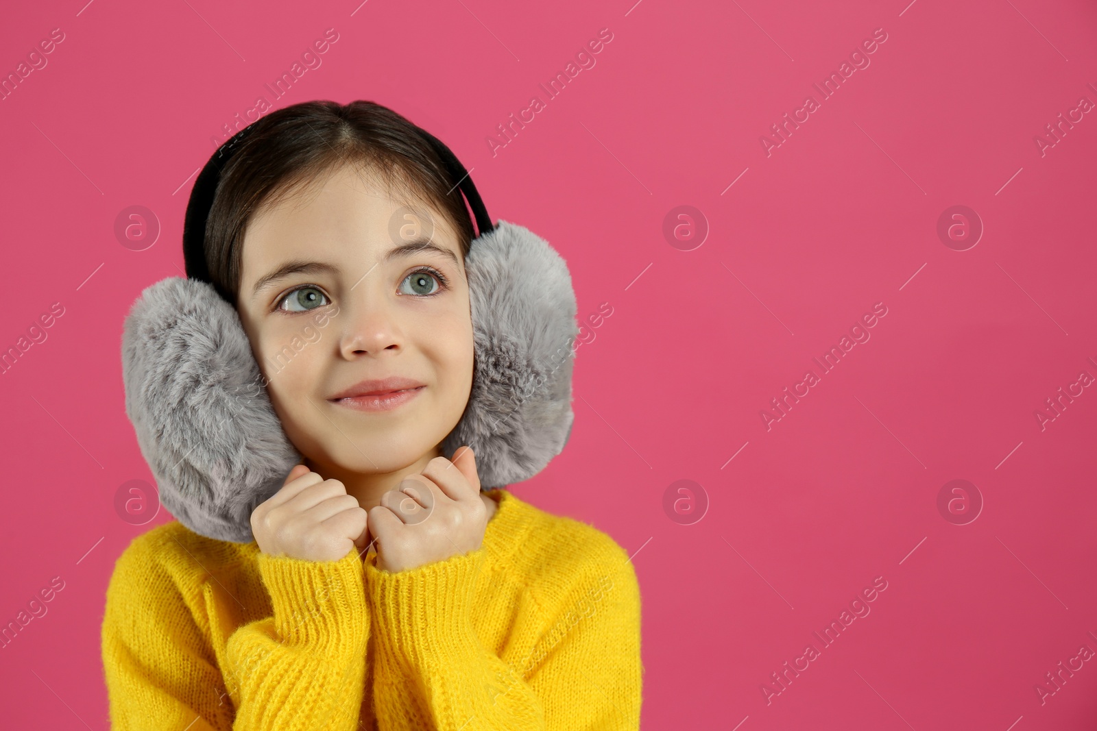 Photo of Cute little girl wearing stylish earmuffs on pink background. Space for text