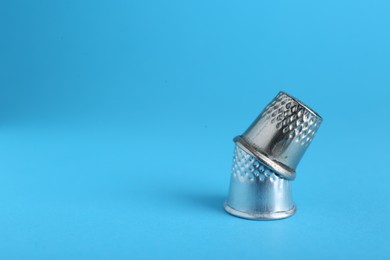 Photo of Sewing thimbles on light blue background, closeup. Space for text