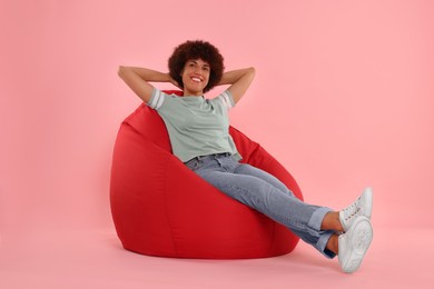 Photo of Beautiful young woman sitting on beanbag chair against pink background