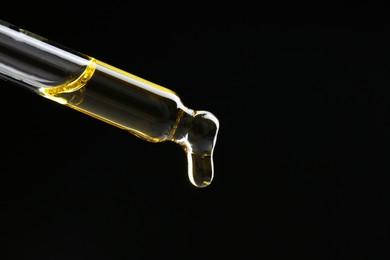 Photo of Dripping tincture from pipette on black background, closeup. Space for text