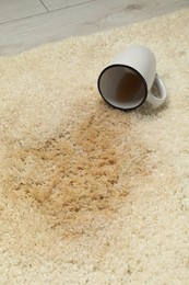 Photo of Overturned cup and spilled drink on beige carpet, closeup
