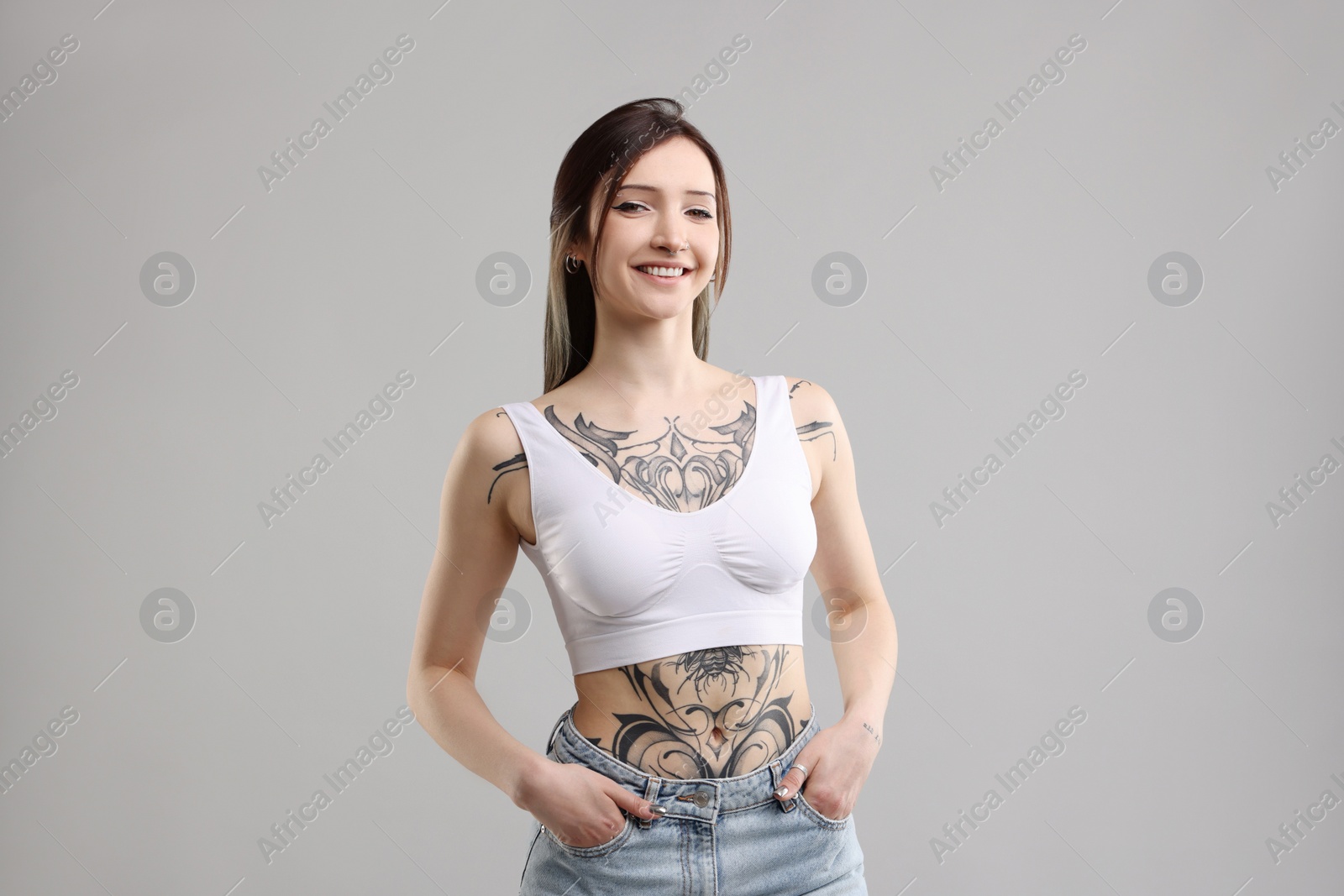 Photo of Portrait of smiling tattooed woman on grey background