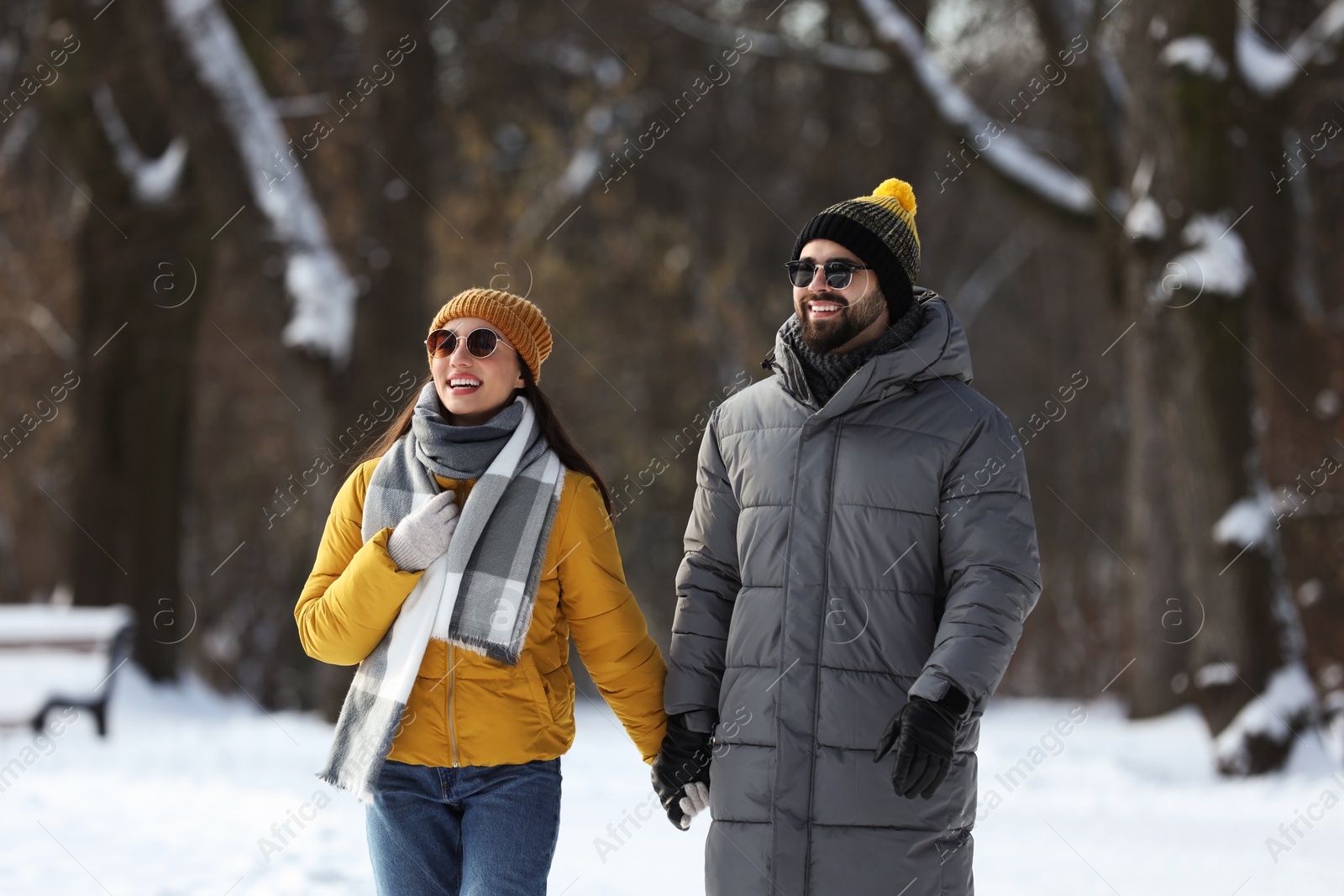 Photo of Happy young couple walking in snowy park on winter day