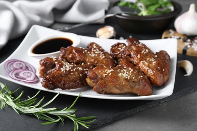 Photo of Chicken wings glazed with soy sauce served on grey table, closeup