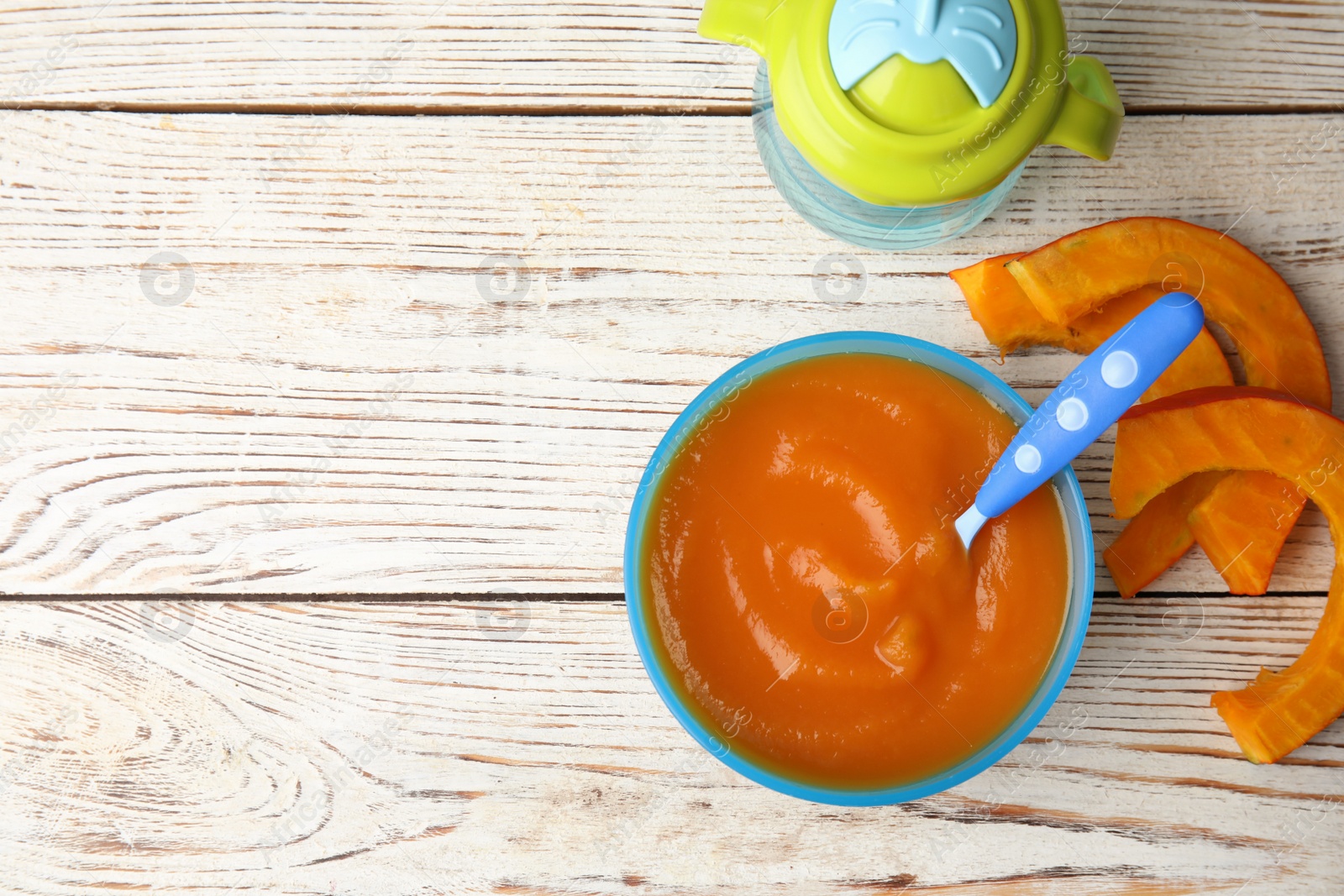 Photo of Flat lay composition with bowl of healthy baby food and space for text on wooden background