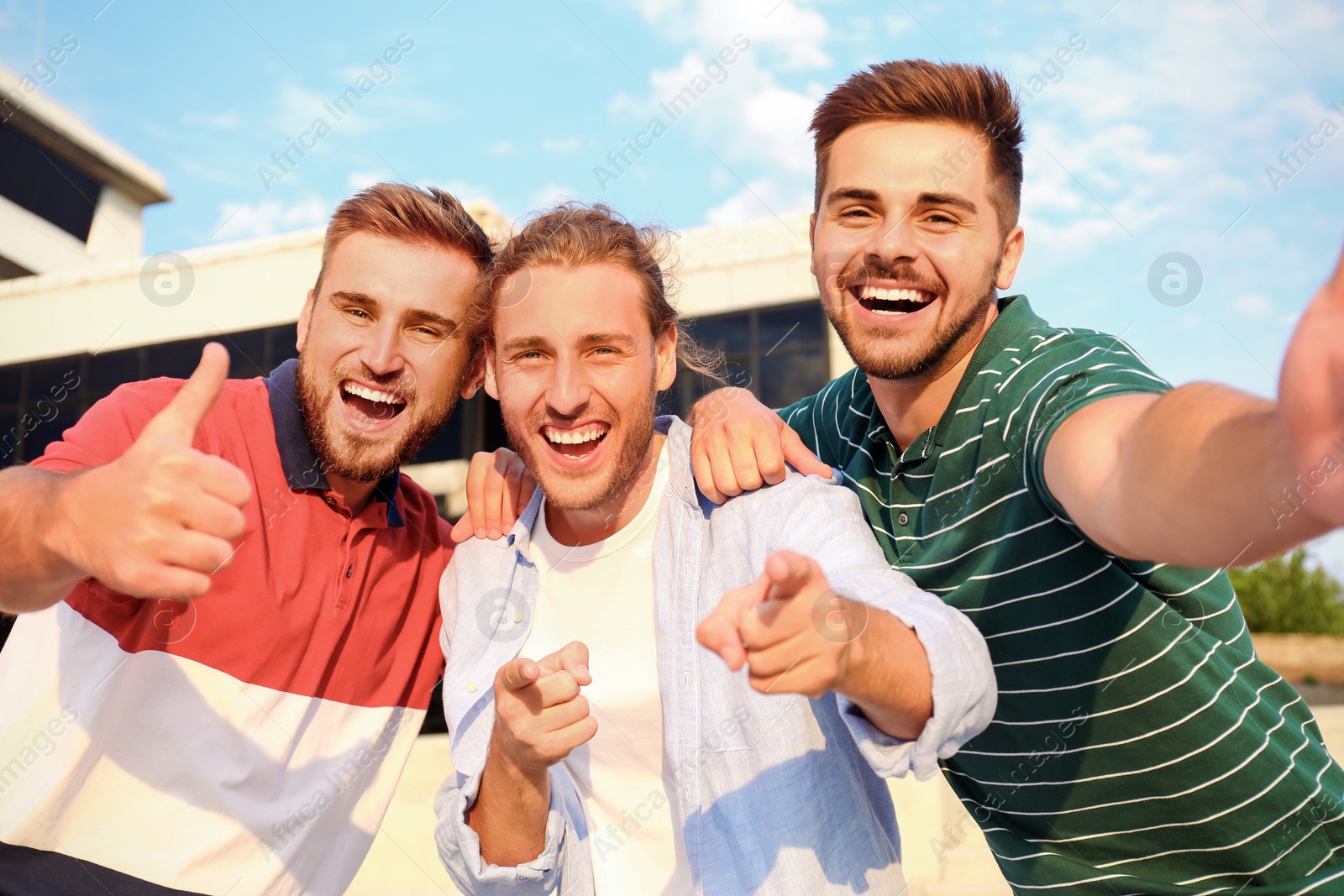 Photo of Happy young men taking selfie outdoors on sunny day