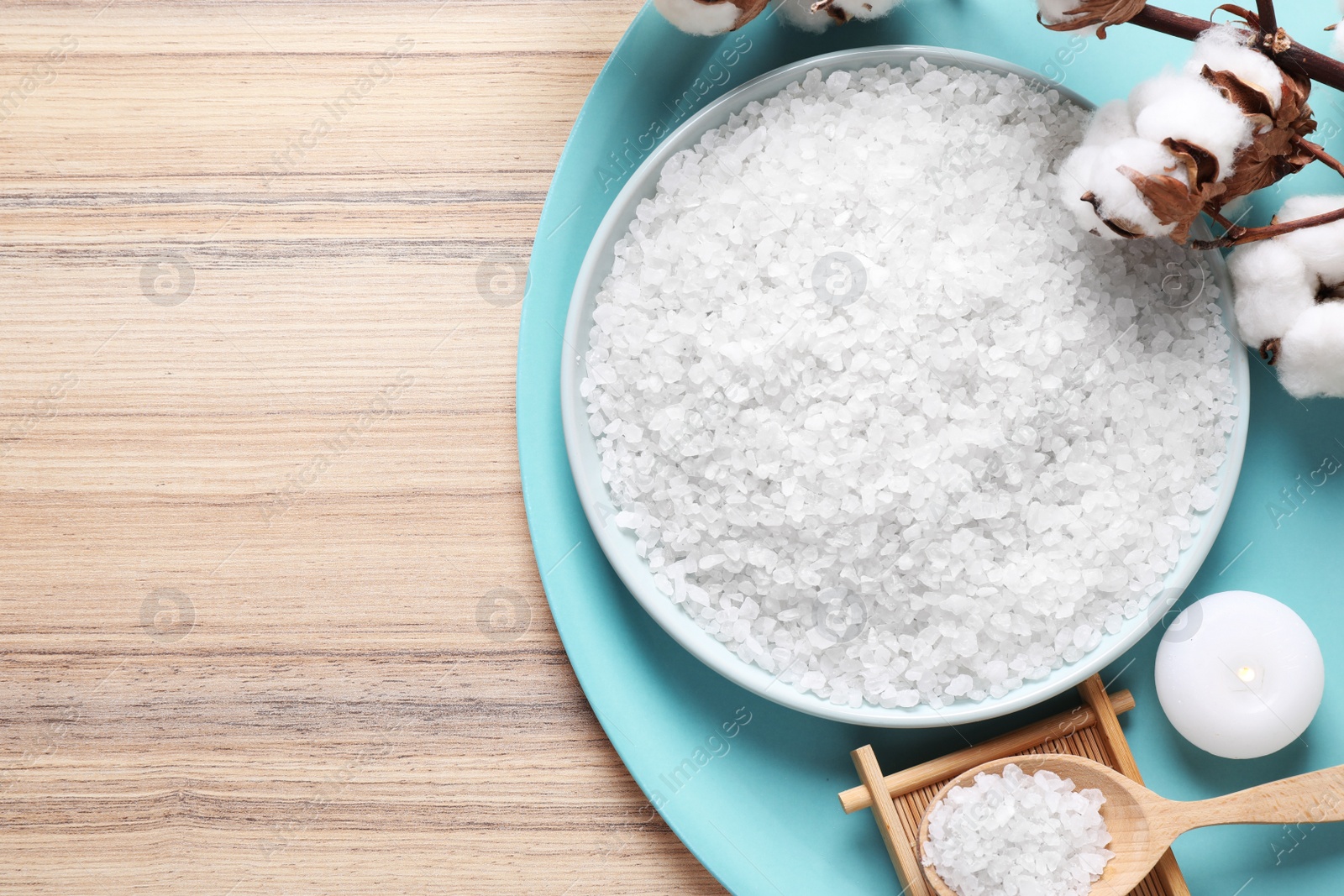 Photo of White sea salt for spa scrubbing procedure and cotton on wooden background, flat lay