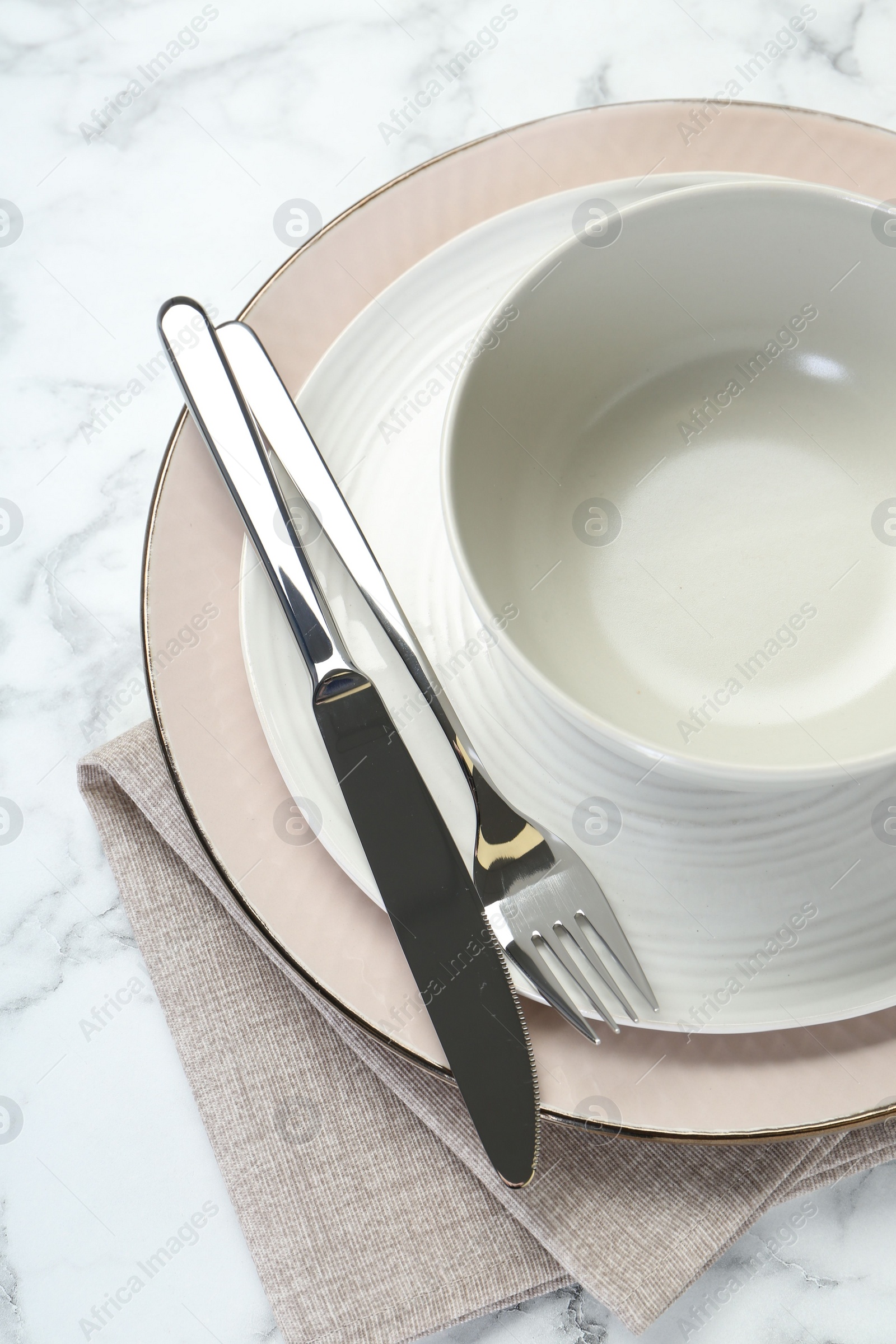 Photo of Clean plates, bowl, cutlery and napkin on white table, top view