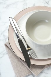 Clean plates, bowl, cutlery and napkin on white table, top view