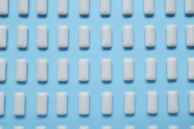 Tasty white chewing gums on light blue background, flat lay