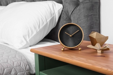 Photo of Stylish alarm clock and decor on nightstand in bedroom. Space for text