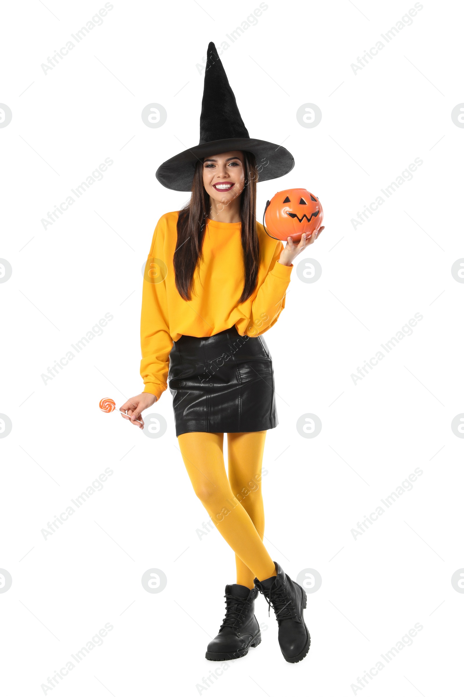 Photo of Beautiful woman wearing witch costume with Jack O'Lantern candy container for Halloween party on white background