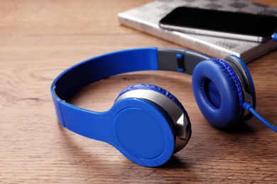 Photo of Modern headphones, notebook and smartphone on wooden table