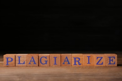 Photo of Wooden cubes with word Plagiarize on table, space for text