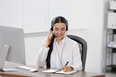 Hotline operator with headset and notebook working in office