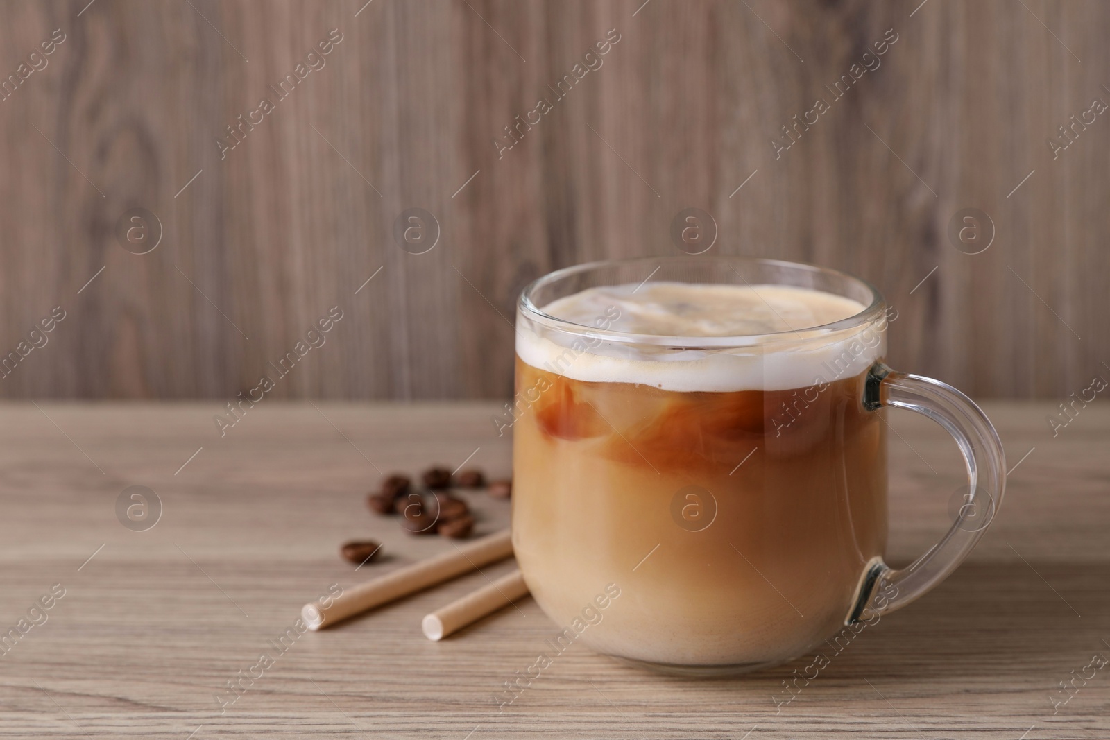 Photo of Fresh coffee, beans and straws on wooden table. Space for text