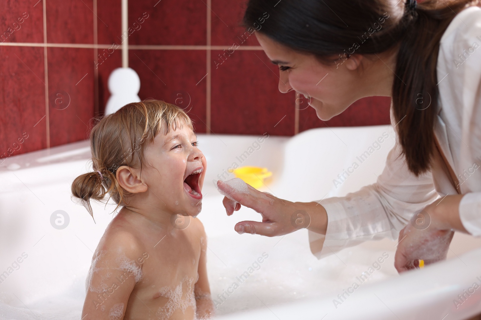 Photo of Happy mother with her little daughter spending time together in bathroom