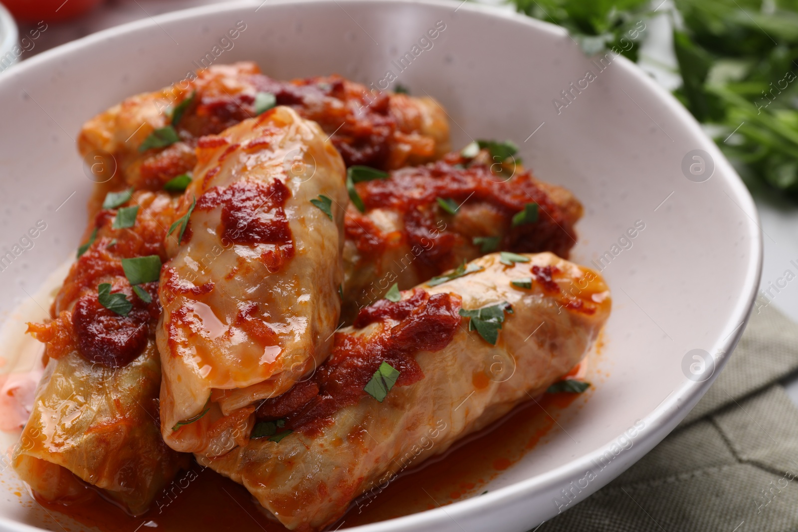 Photo of Delicious stuffed cabbage rolls cooked with homemade tomato sauce on table, closeup