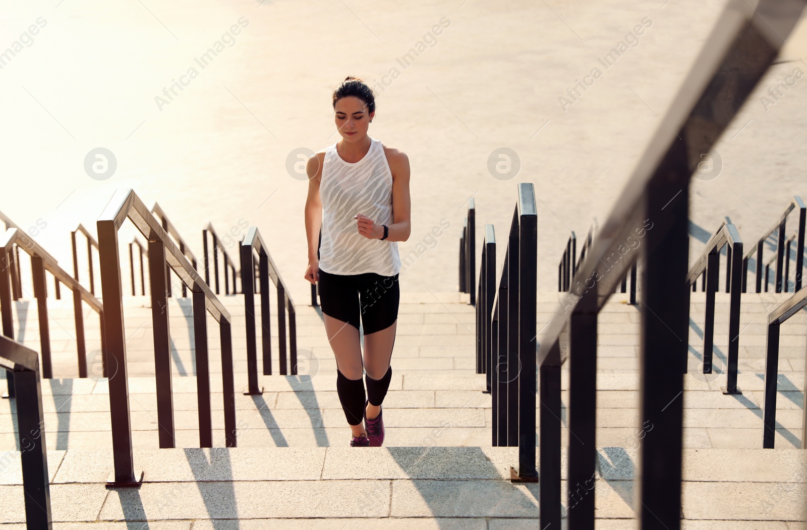 Photo of Sporty young woman running upstairs on sunny day