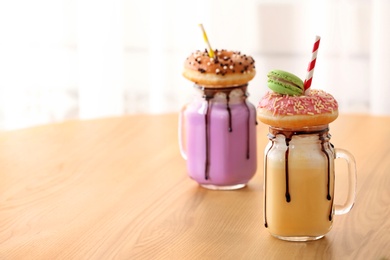 Photo of Mason jars with delicious milk shakes on table. Space for text