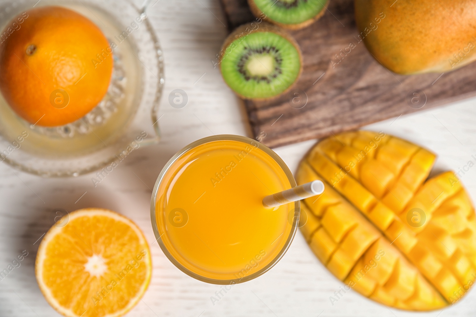 Photo of Glass of fresh mango drink and tropical fruits on table, top view