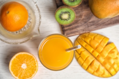 Glass of fresh mango drink and tropical fruits on table, top view