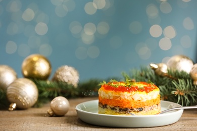 Photo of Traditional russian salad Mimosa and festive decor on table against blurred lights