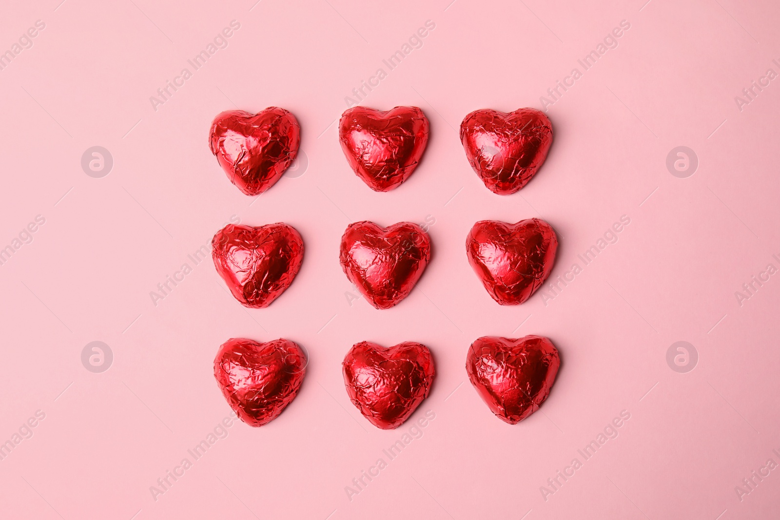 Photo of Heart shaped chocolate candies on pink background, flat lay. Valentine's day treat