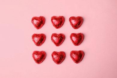Photo of Heart shaped chocolate candies on pink background, flat lay. Valentine's day treat