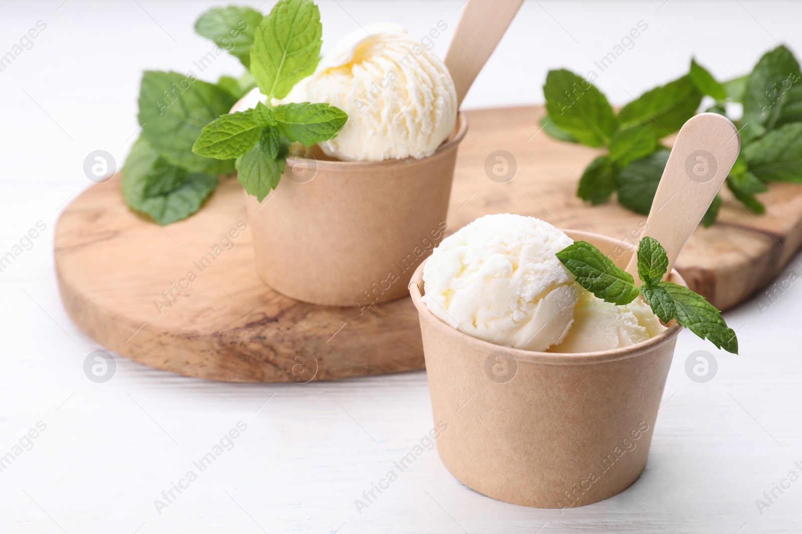 Photo of Delicious vanilla ice cream and mint on white wooden table