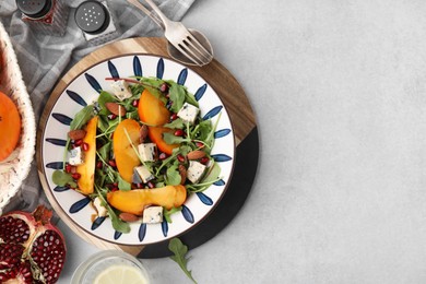 Tasty salad with persimmon, blue cheese, pomegranate and almonds served on white table, flat lay. Space for text