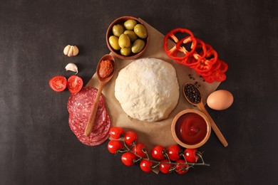 Pizza dough and products on dark table, flat lay